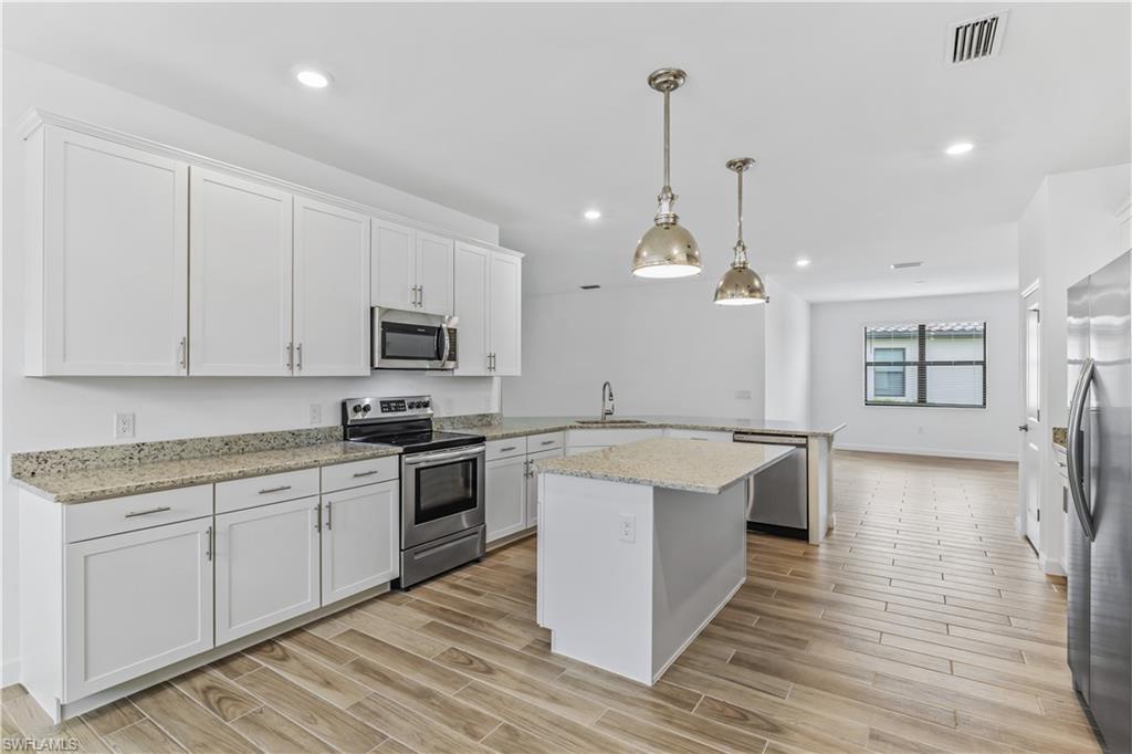 1817 Lema Court Naples, FL 34120 - Photo 3 of 22 a large kitchen with stainless steel appliances granite countertop a sink a stove and a wooden floors