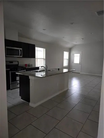 a kitchen with granite countertop a stove a sink and a microwave