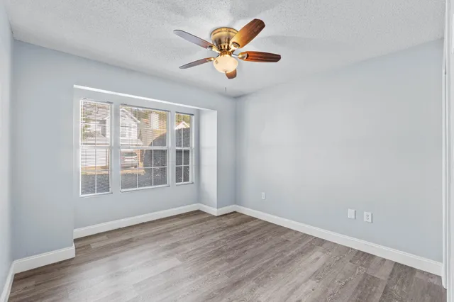an empty room with wooden floor and windows