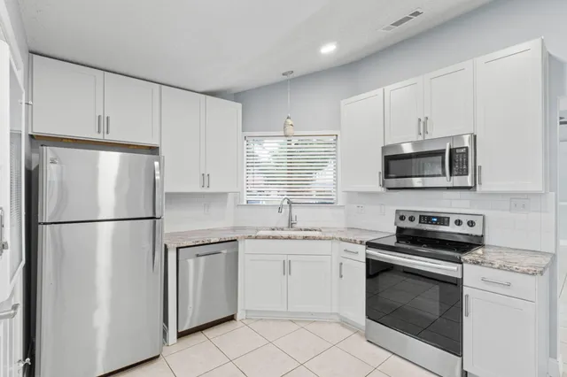 a kitchen with white cabinets and white appliances