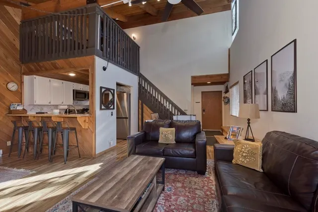 a living room with furniture kitchen view and a wooden floor