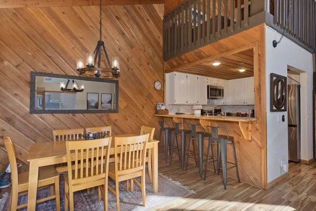 a kitchen view with stainless steel appliances kitchen island granite countertop a table chairs and a refrigerator