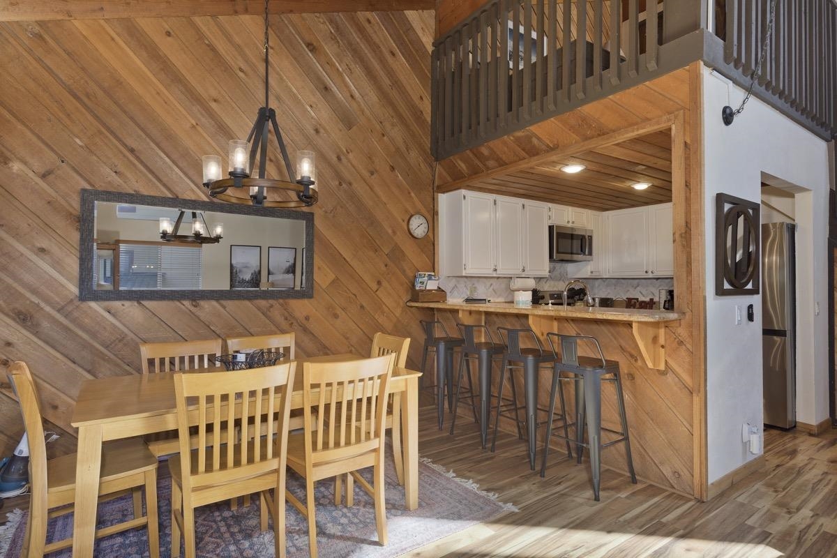 175 Mammoth Slopes Drive, Unit 3 Mammoth Lakes, CA 93546 - Photo 6 of 30 a kitchen view with stainless steel appliances kitchen island granite countertop a table chairs and a refrigerator