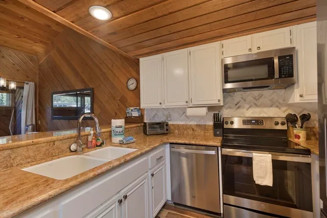 a kitchen with stainless steel appliances a stove a sink and white cabinets