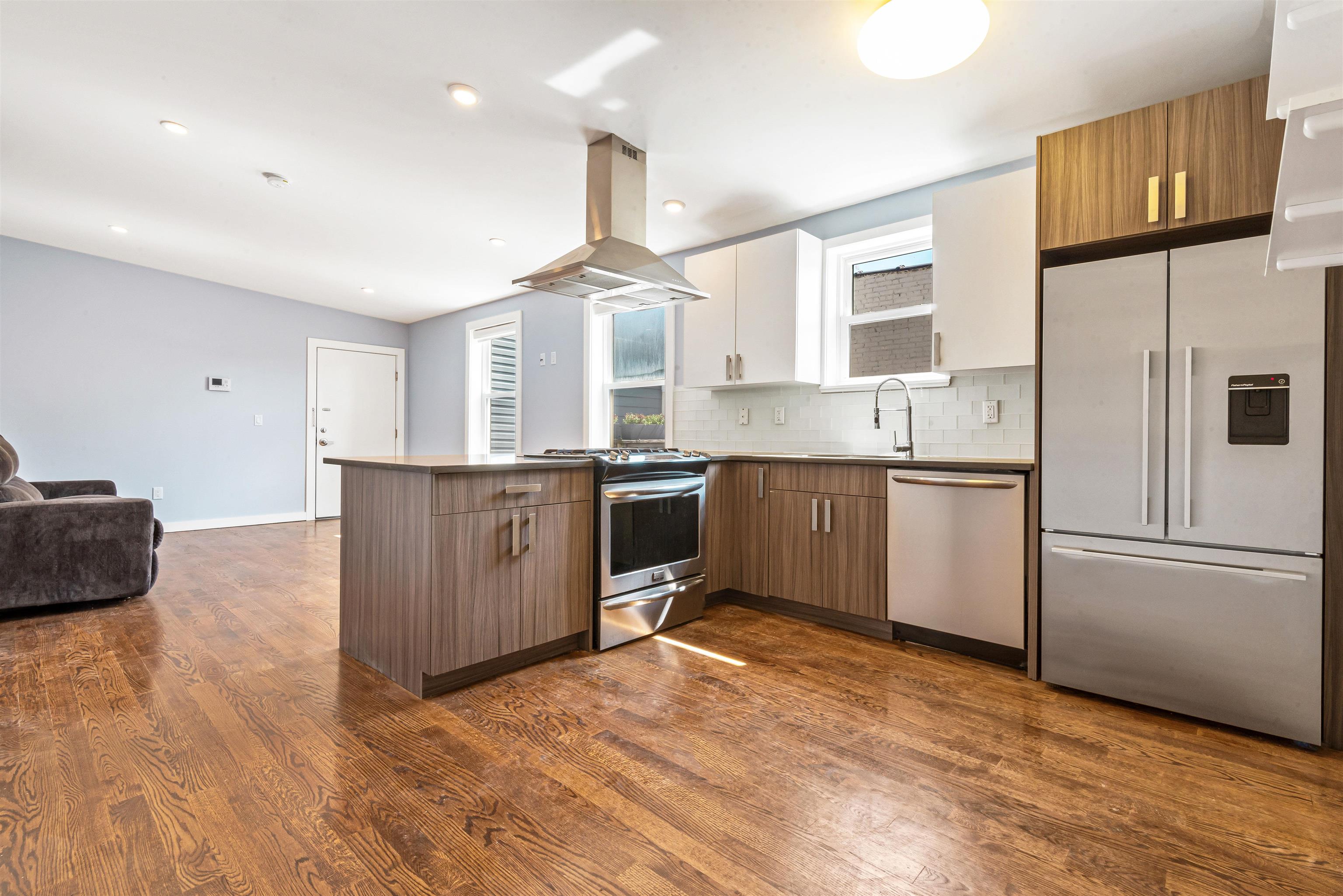 102 Colgate Street, Unit 302 Jersey City, NJ 07302 - Photo 11 of 21 a kitchen with stainless steel appliances granite countertop a stove a sink dishwasher a refrigerator and white cabinets with wooden floor