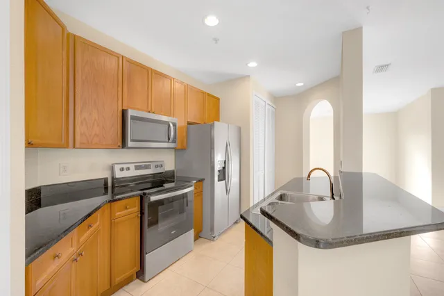 a kitchen with stainless steel appliances granite countertop a sink a stove and a refrigerator