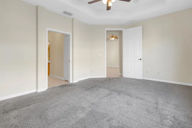a view of an empty room and chandelier fan