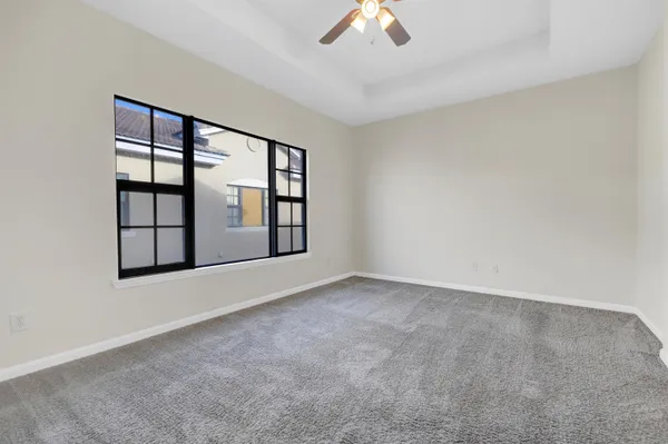 an empty room with windows and chandelier fan