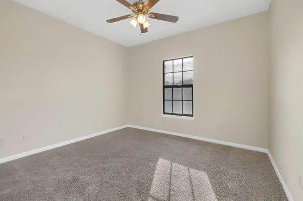 an empty room with windows and fan