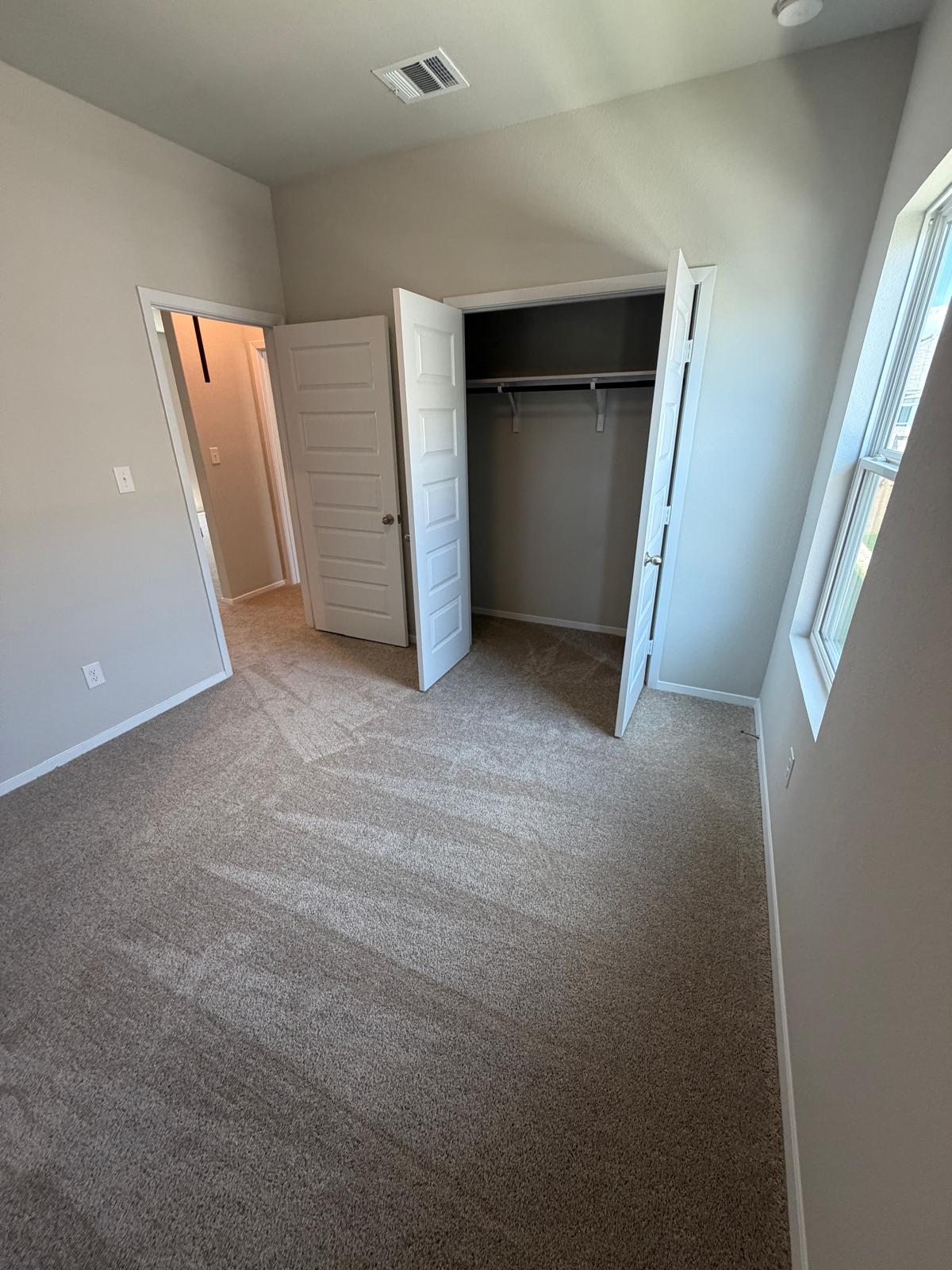 2612 Towy Road Manor, TX 78653 - Photo 14 of 35 A well-lit bedroom features plush carpeting and a convenient walk-in closet.