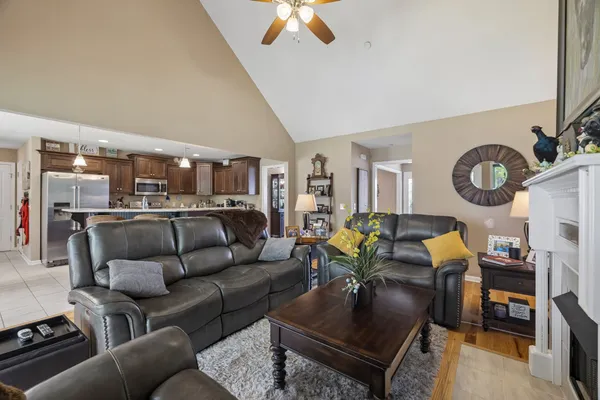 a kitchen with stainless steel appliances granite countertop a refrigerator a sink dishwasher a stove and a dining table with wooden floor