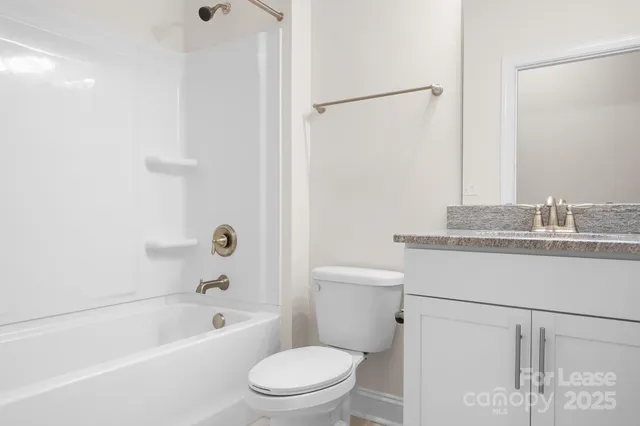 a bathroom with a granite countertop sink a toilet and shower
