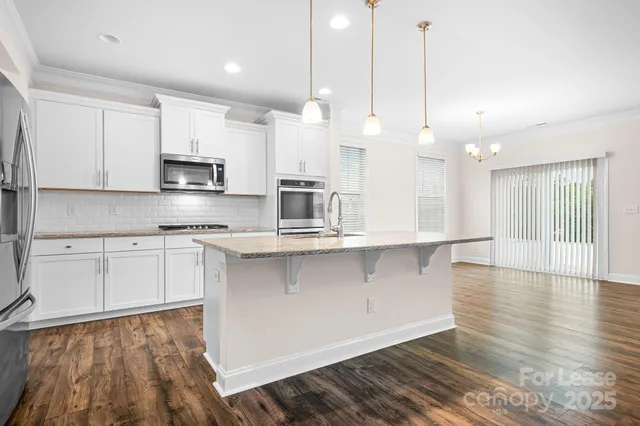 a open kitchen with kitchen island a stove a sink a center island and wooden floor