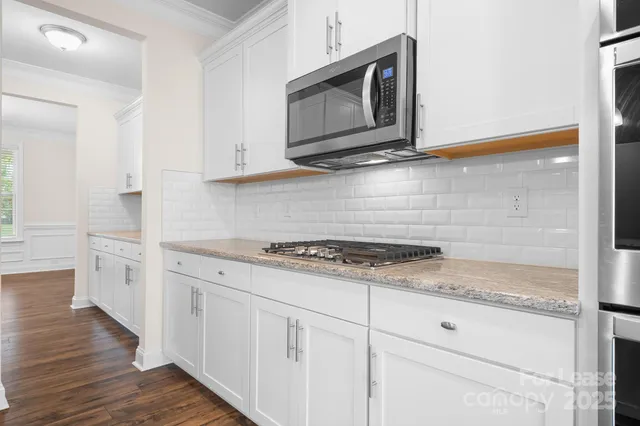 a kitchen with stainless steel appliances granite countertop white cabinets and stove