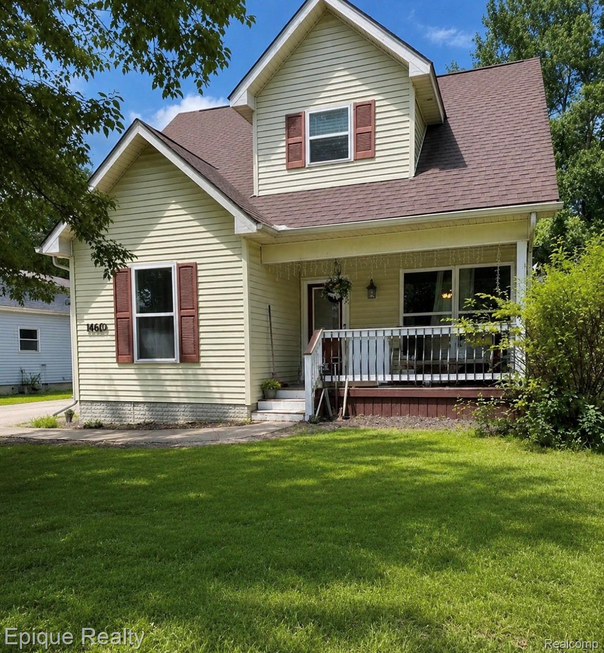 11619 Read Avenue Mount Morris, MI 48458 - Photo 1 of 10 Two-story residence featuring light yellow siding, a covered front porch with white railing, and dark brown shutters