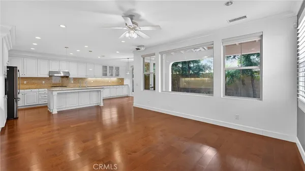 a view of a kitchen with kitchen island a window wooden floor and stainless steel appliances
