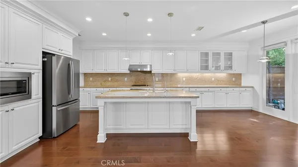 a kitchen with kitchen island a counter top space a sink stainless steel appliances and cabinets