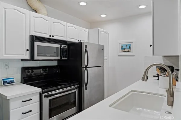 a kitchen with refrigerator a stove a sink and cabinets