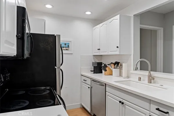 a kitchen with stainless steel appliances a stove a sink a microwave a refrigerator and white cabinets