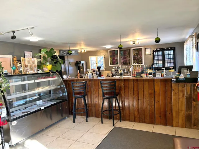 a dining hall with stainless steel appliances kitchen island granite countertop a table chairs in it and a window