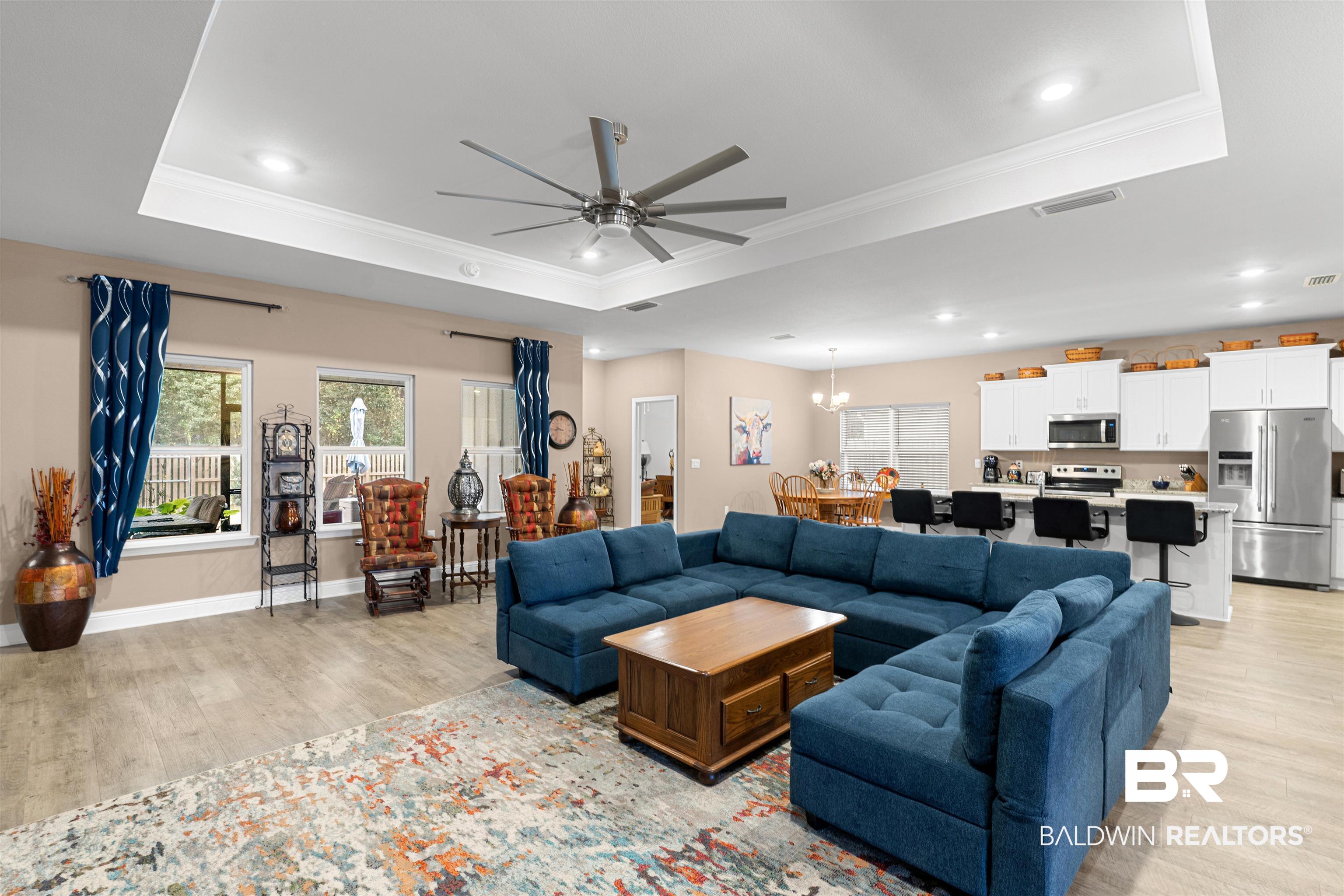 697 Calibre Street Fairhope, AL 36532 - Photo 5 of 18 Living room with light wood-style flooring, ceiling fan, crown molding, a tray ceiling, and healthy amount of natural light