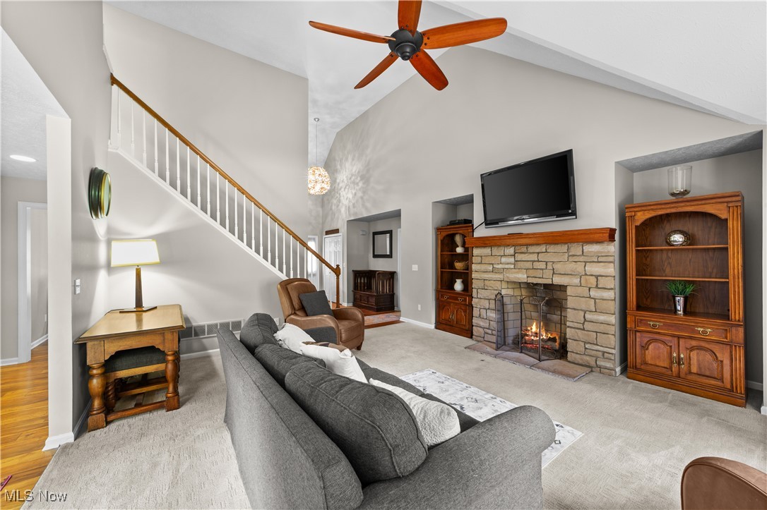 30825 Cannon Road Solon, OH 44139 - Photo 7 of 49 Carpeted living area featuring high vaulted ceiling, a fireplace, ceiling fan, and stairs