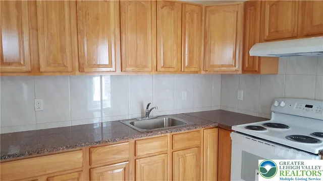 a kitchen with granite countertop a sink a stove and dishwasher