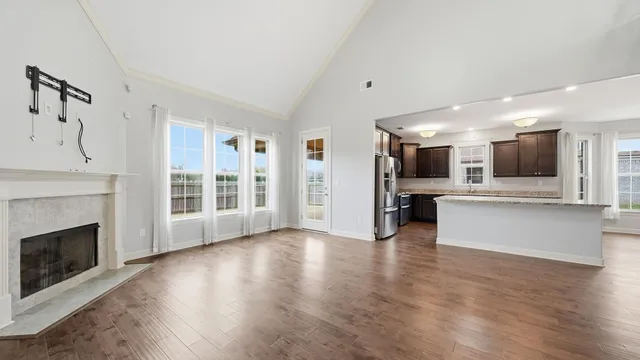 a view of an empty room with wooden floor fireplace and a window