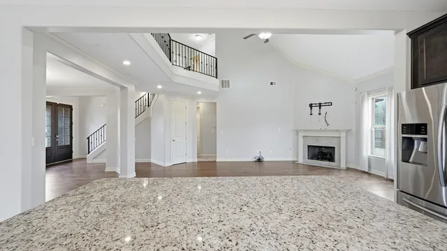 a view of a hallway with wooden floor and a kitchen