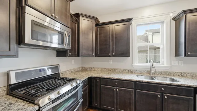 a large kitchen with stainless steel appliances granite countertop a stove and large cabinets