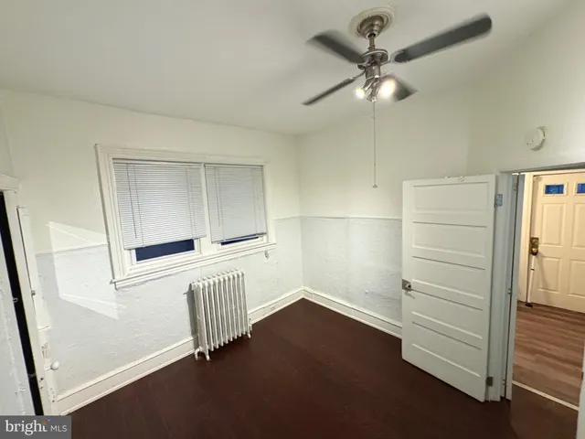 an empty room with wooden floor cabinet and windows