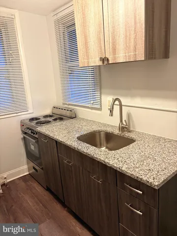 a kitchen with granite countertop a sink a stove and cabinets