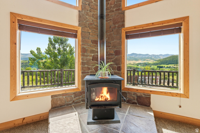 306 Spring Road Preston, ID 83263 - Photo 8 of 55 Corner wood-burning stove with a stone surround, complemented by natural wood window frames