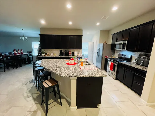a kitchen with stainless steel appliances kitchen island granite countertop a table and chairs