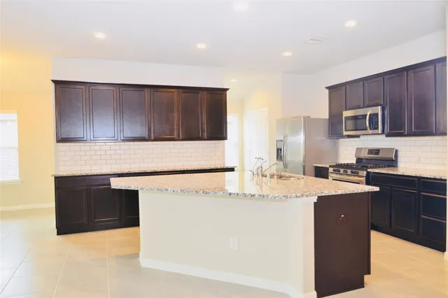 a kitchen with stainless steel appliances granite countertop a sink a stove a microwave and a refrigerator