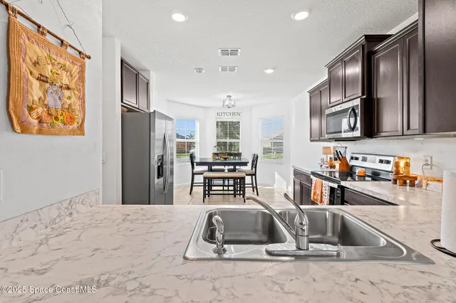 a room with stainless steel appliances kitchen island granite countertop a refrigerator and a sink