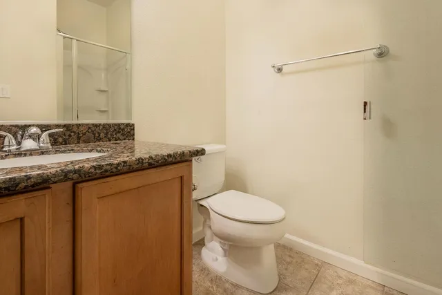 a bathroom with a granite countertop sink toilet and a mirror