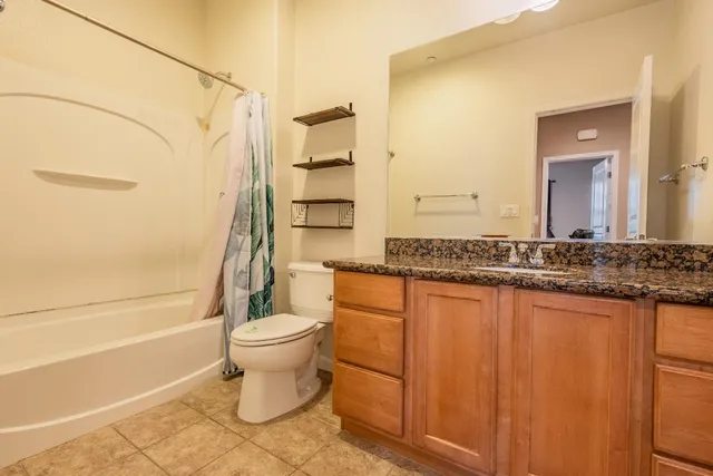 a bathroom with a granite countertop toilet and a sink