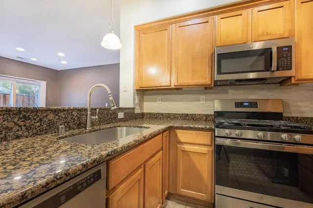 a kitchen with granite countertop a sink stainless steel appliances and cabinets