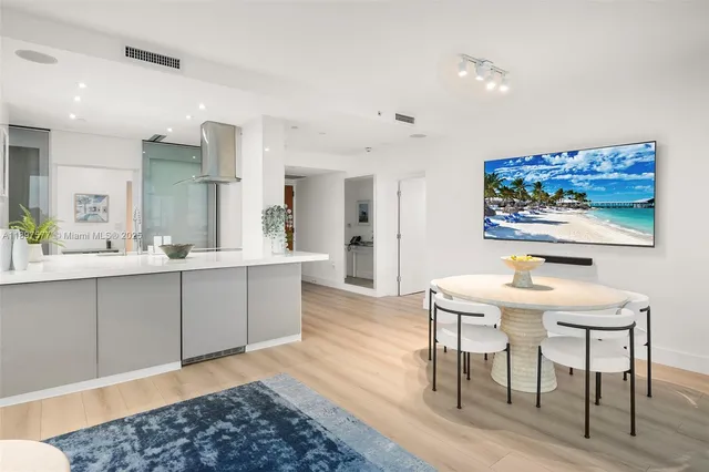 a kitchen with stainless steel appliances kitchen island granite countertop a dining table chairs and a refrigerator