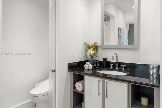 a bathroom with a granite countertop sink and a toilet