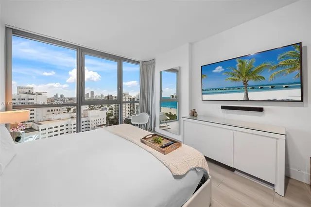 a bedroom with a bed painting on wall and a large window