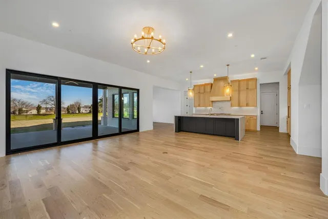 a view of an empty room with a window and kitchen view