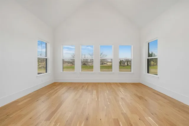 a view of empty room with wooden floor and fan
