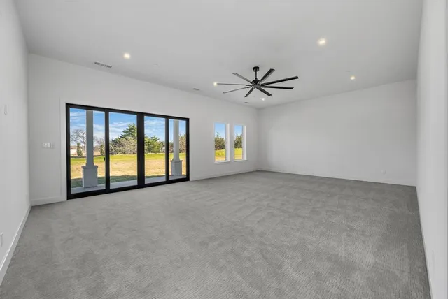 a view of an empty room with a window and a ceiling fan