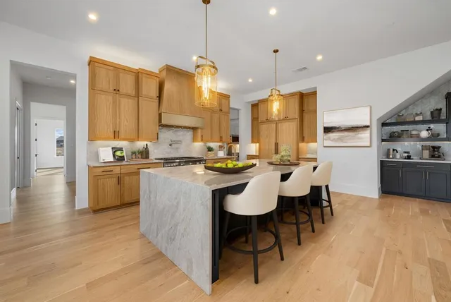 a kitchen with stainless steel appliances kitchen island granite countertop a stove a sink dishwasher a refrigerator and cabinets with wooden floor