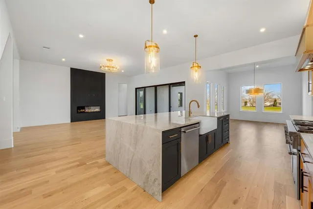 a large kitchen with stainless steel appliances a large counter top a stove and a refrigerator