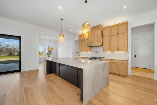 a kitchen with kitchen island a stove a sink a center island and wooden floor