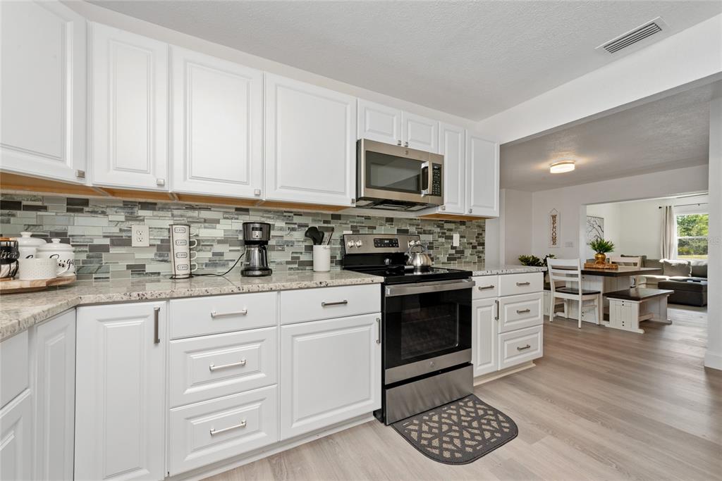 52 North York Road Avon Park, FL 33825 - Photo 12 of 44 a kitchen with stainless steel appliances granite countertop a stove top oven a sink dishwasher and white cabinets with wooden floor