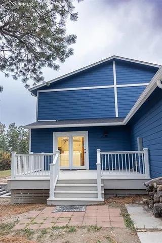 a wooden house with large trees in front of it